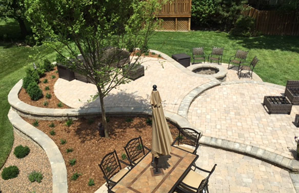 outdoor living space, example of hardscaping and hardscape design, featuring a patio dining set and mulch bed with small shrubs.