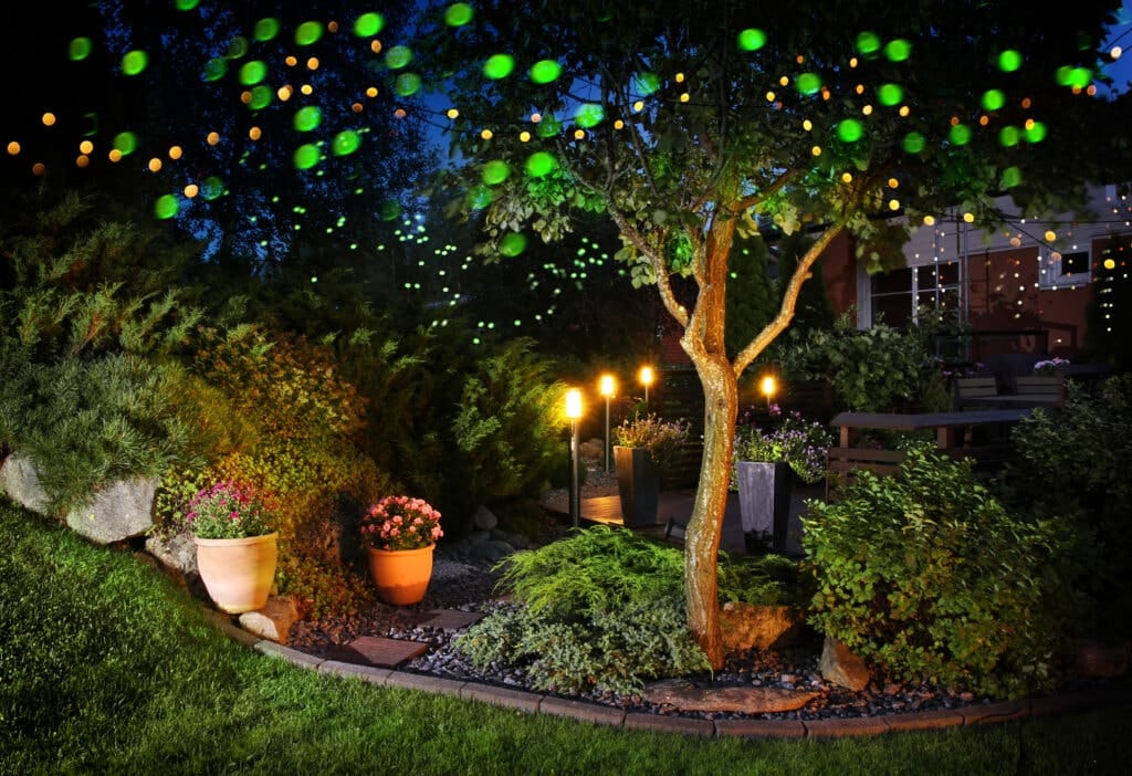 view of entryway into landscaped patio at night with lights along walkway