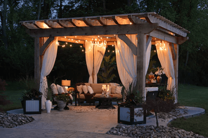 Gazebo decorated with lights with patio furniture in the evening