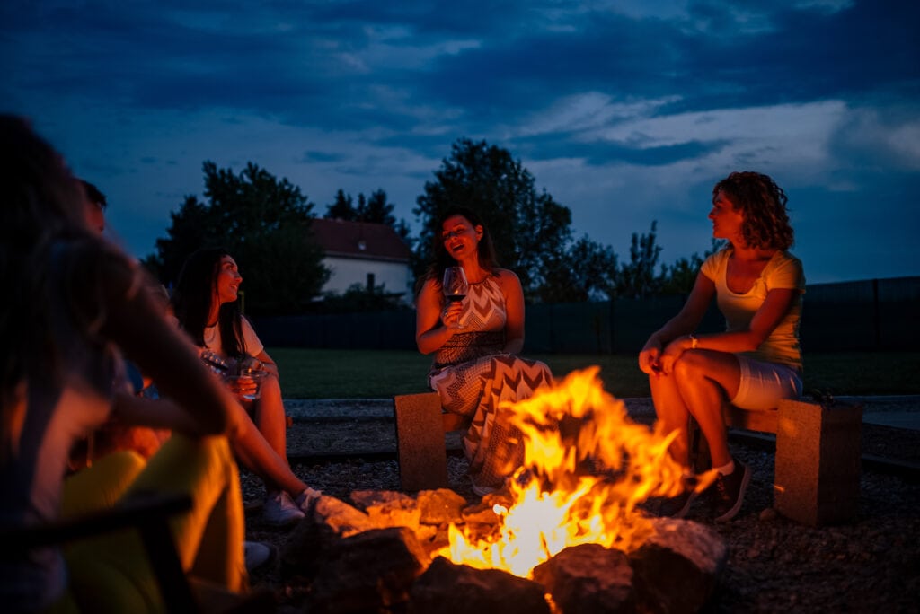 Friends sitting around firepit on summer evening