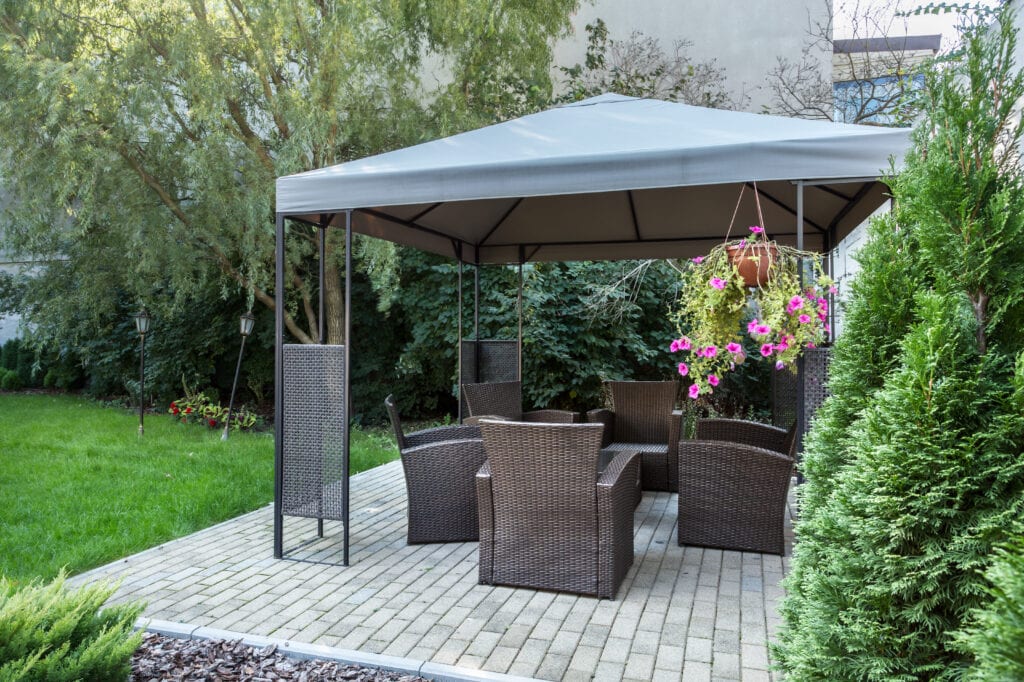 Patio and Gazebo in backyard, featuring grey wicker chairs, example of summer hardscaping and hardscape design.