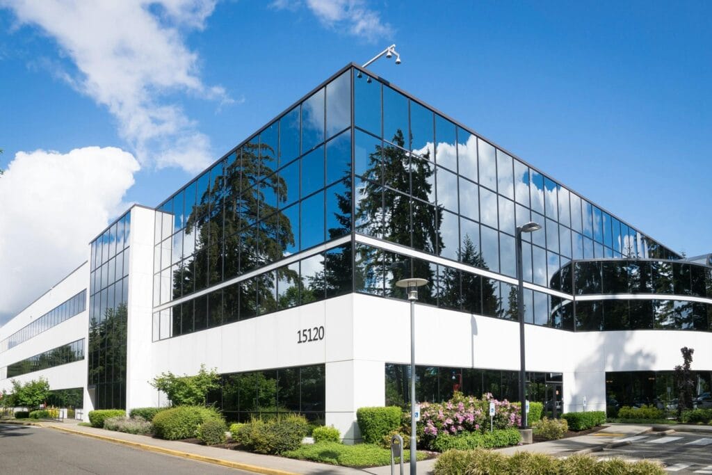 The landscape of a commercial property, portraying beautiful bushes and flowers decorating a new white and windowed property.