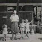 A black-and-white photo of a man in an apron standing outside Walnut Ridge with three children, the original family of the local landscaping company.